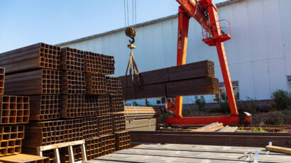 Gantry crane transporting stack of metal pipes in the steel factory